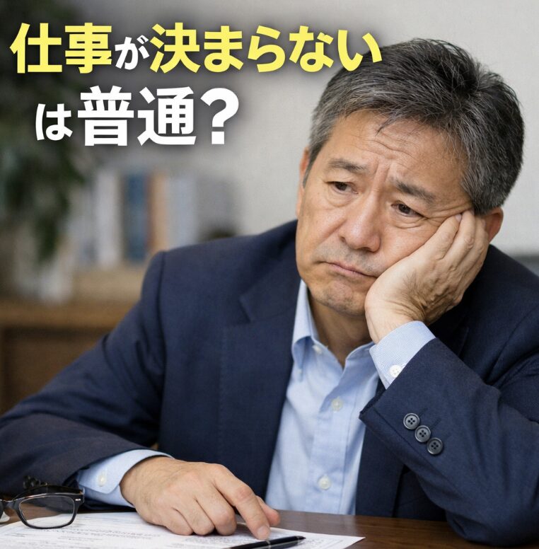 50代男性が机に肘をつき、履歴書を前に不安そうに悩んでいる様子と「仕事が決まらないは普通？」の文字